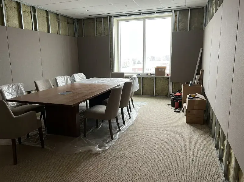 Vergaderzaal met akoestische wandpanelen in stof en een gedempte tapijtvloer
